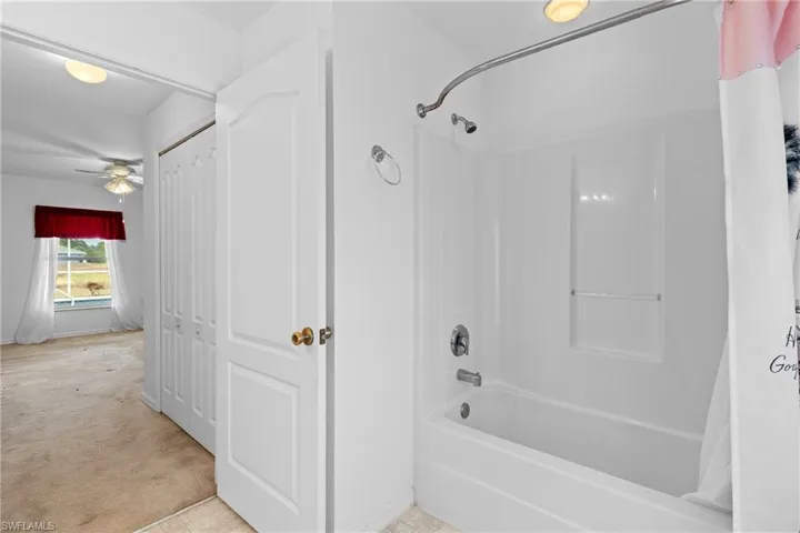 Full bath with shower / bath combination with curtain and light carpet