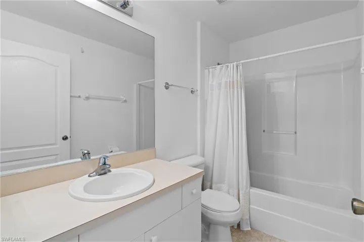 Full bathroom with shower / bathtub combination with curtain, vanity, and light tile patterned floors