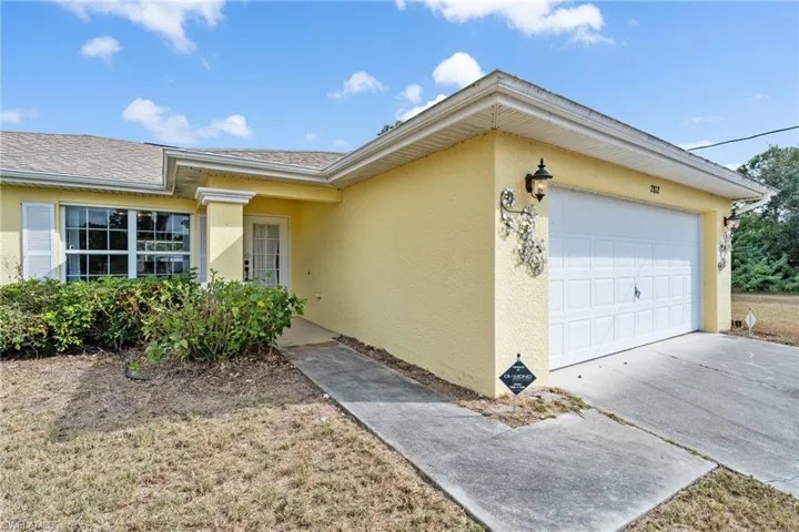 View of front of house with stucco siding, an attached garage, driveway, and a shingled roof