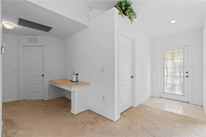 Foyer entrance with light carpet and baseboards