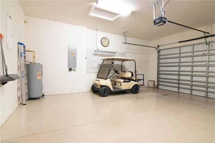 Garage with water heater, electric panel, and a garage door opener