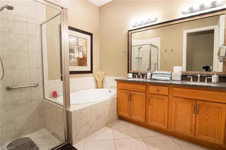 Bathroom with a shower stall, a garden tub, double vanity, and light tile patterned floors