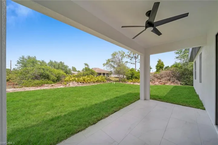 View of green lawn featuring ceiling fan and a patio