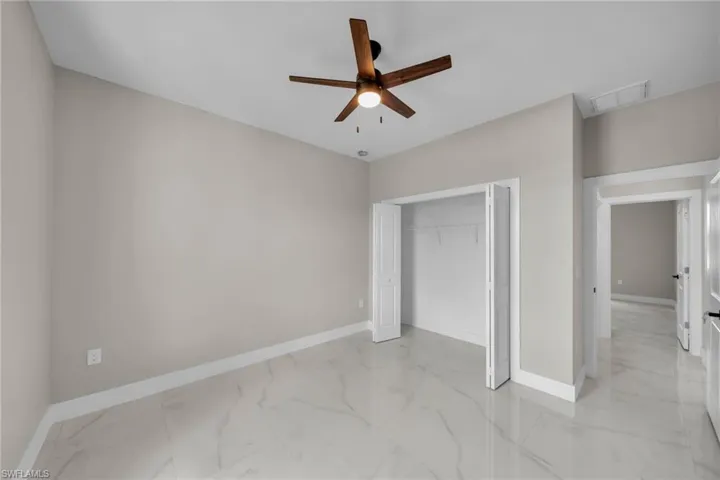 Unfurnished bedroom with light marble finish flooring, a closet, and a ceiling fan
