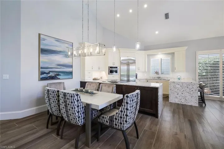 Dining area featuring dark wood-type flooring and high vaulted ceiling
