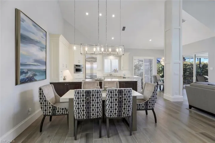Dining space with sink, high vaulted ceiling, light hardwood / wood-style flooring, and plenty of natural light