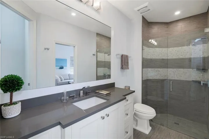 Bathroom featuring vanity, toilet, wood-type flooring, and a shower with shower door