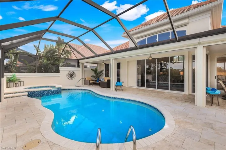 View of pool with a patio area and glass enclosure