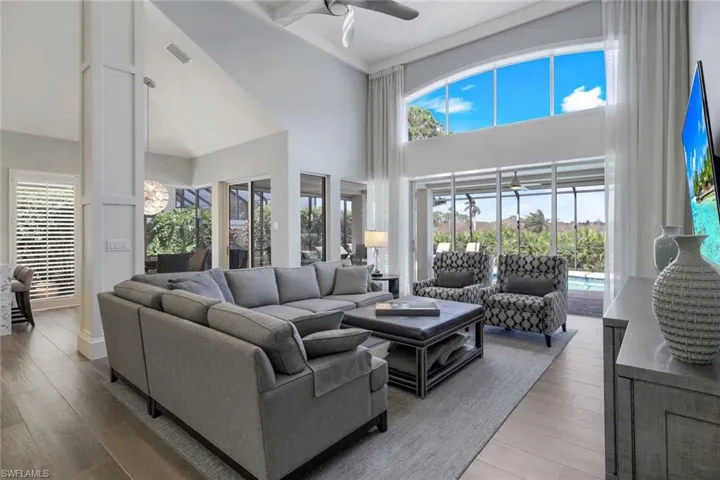 Living room featuring light hardwood / wood-style flooring, ceiling fan, a high ceiling, and a wealth of natural light