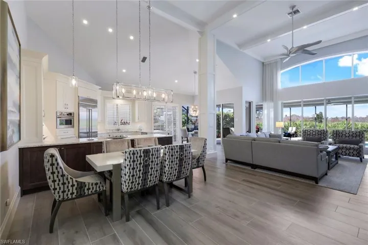 Dining room with ceiling fan, high vaulted ceiling, wood-type flooring, and beamed ceiling