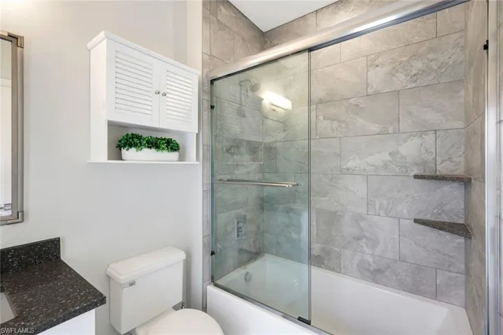 Full bathroom featuring vanity, shower / bath combination with glass door, and toilet