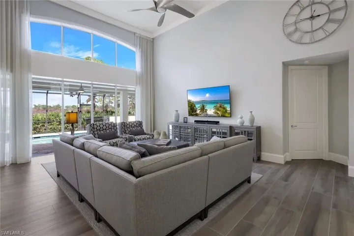 Living room featuring a towering ceiling, wood-type flooring, and ceiling fan