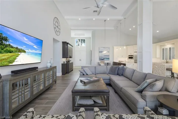 Living room with beam ceiling, dark hardwood / wood-style floors, high vaulted ceiling, and ceiling fan