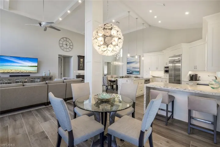 Dining area with high vaulted ceiling, dark wood-type flooring, and ceiling fan with notable chandelier