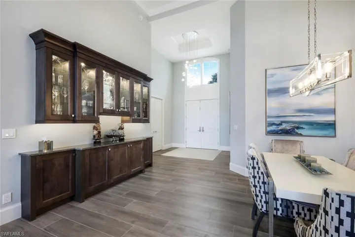 Bar featuring dark brown cabinetry, hardwood / wood-style floors, hanging light fixtures, and an inviting chandelier