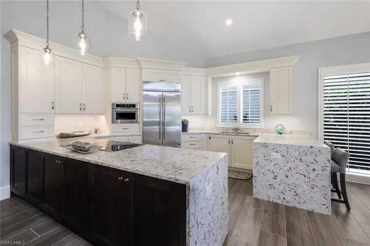 Kitchen featuring a center island, dark hardwood / wood-style flooring, stainless steel appliances, lofted ceiling, and pendant lighting