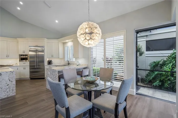 Dining room with high vaulted ceiling, sink, a chandelier, and dark hardwood / wood-style floors