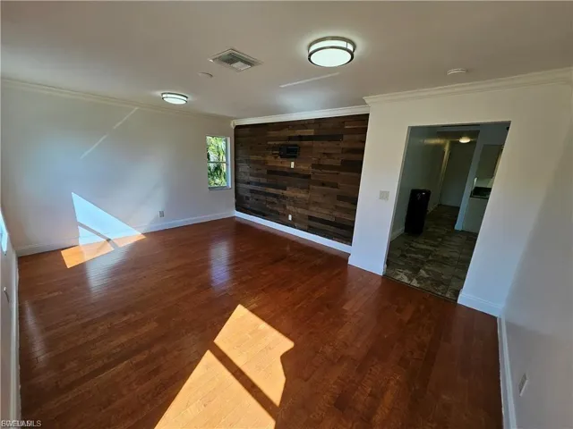 Unfurnished room featuring crown molding, dark wood-style flooring, and wooden walls