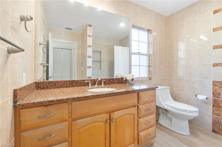 Bathroom featuring tile walls, vanity, a shower with shower curtain, and light wood-type flooring