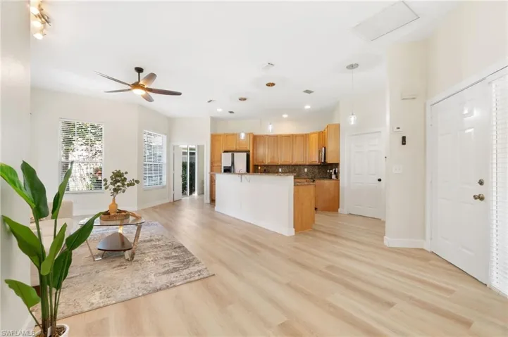 Kitchen featuring decorative light fixtures, stainless steel fridge, open floor plan, backsplash, and light wood finished floors