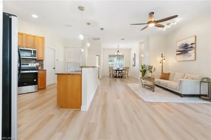 Kitchen with appliances with stainless steel finishes, dark stone counters, open floor plan, decorative light fixtures, and decorative backsplash
