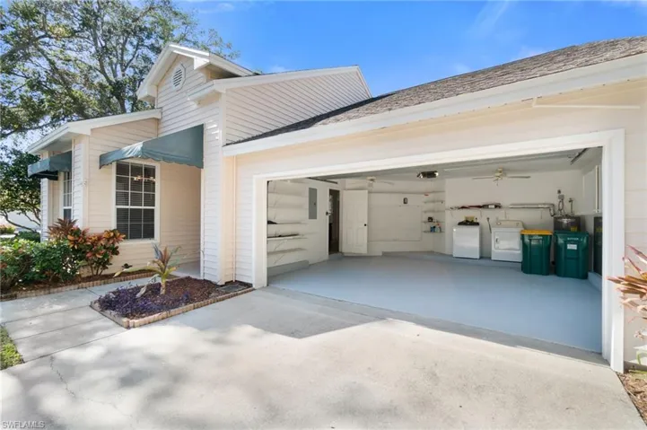 View of side of property featuring driveway, a garage, and washing machine and clothes dryer