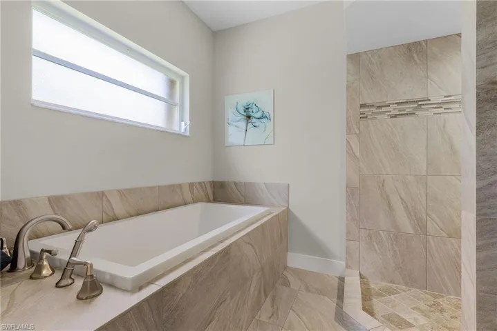 Bathroom featuring a relaxing tiled bath and tile flooring