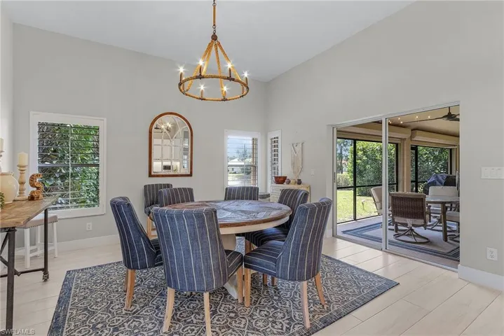 Dining area featuring vaulted ceiling, a healthy amount of sunlight, light wood-type flooring, and an inviting chandelier