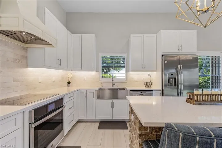 Kitchen featuring white cabinets, stainless steel appliances, tasteful backsplash, sink, and premium range hood