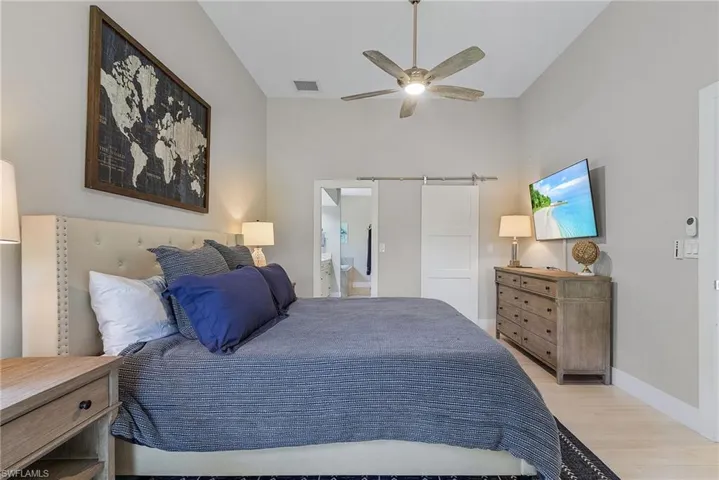Bedroom with ceiling fan, connected bathroom, and light hardwood / wood-style flooring