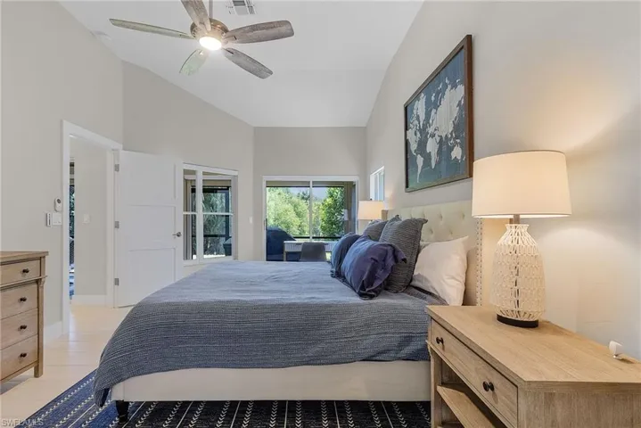 Bedroom featuring ceiling fan, light hardwood / wood-style floors, lofted ceiling, and access to outside