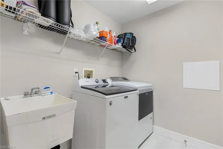 Laundry area featuring washer and dryer, sink, light tile floors, and hookup for a washing machine