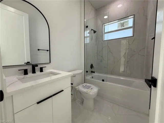Full bath featuring vanity, tub / shower combination, and marble look tile flooring
