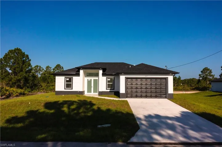 Prairie-style home with french doors, a garage, concrete driveway, a front lawn, and stucco siding