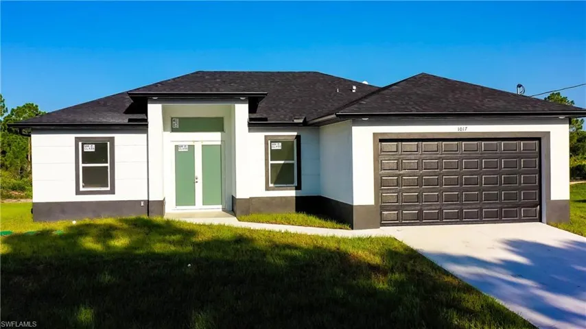 View of front of home with a front yard, an attached garage, stucco siding, concrete driveway, and a shingled roof