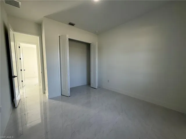 Unfurnished bedroom with a closet and light marble finish floors