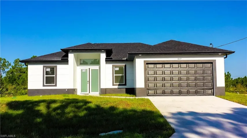 Prairie-style house with an attached garage, driveway, a front lawn, stucco siding, and roof with shingles