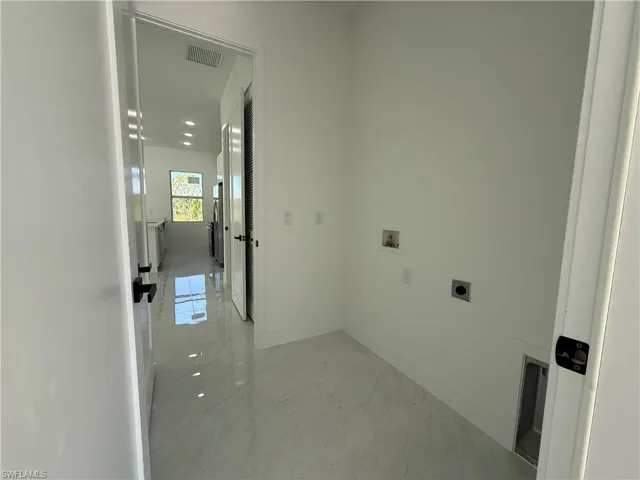 Laundry area with hookup for an electric dryer, hookup for a washing machine, light marble finish flooring, and recessed lighting