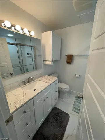 Bathroom with vanity, toilet, and an enclosed shower