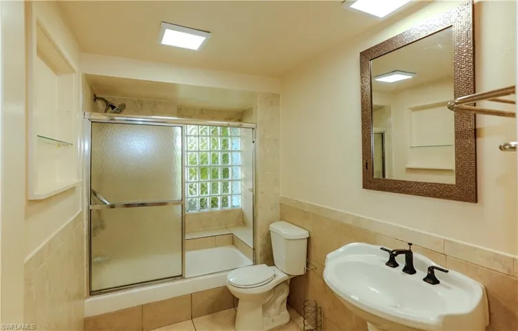 Full bathroom featuring tile walls, wainscoting, a shower stall, and tile patterned flooring