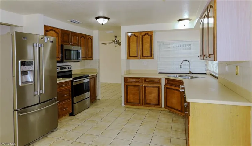Kitchen featuring stainless steel appliances, tasteful backsplash, light tile patterned floors, and brown cabinets