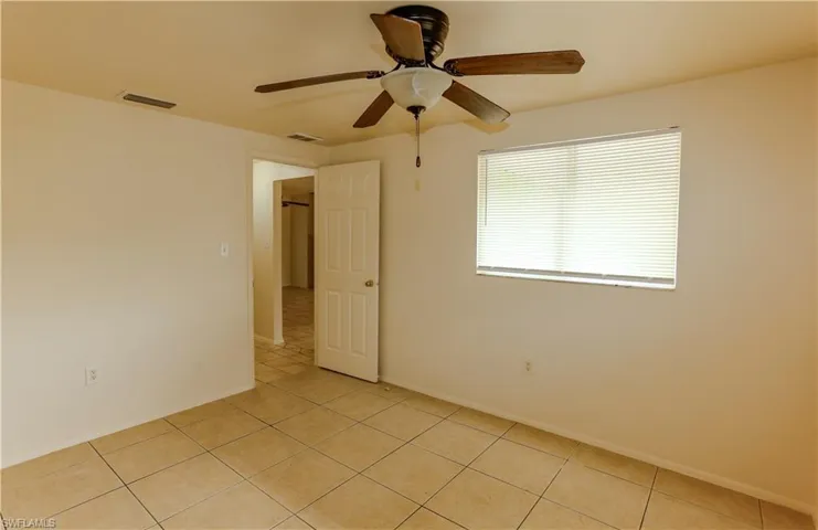 Empty room featuring a ceiling fan and light tile patterned flooring