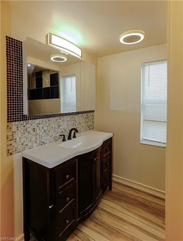 Bathroom with decorative backsplash, vanity, light wood-type flooring, and a shower