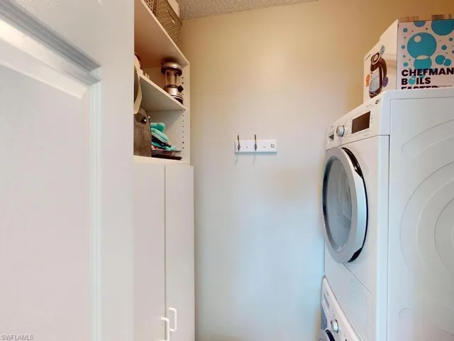 Washroom featuring stacked washer / dryer and a textured ceiling