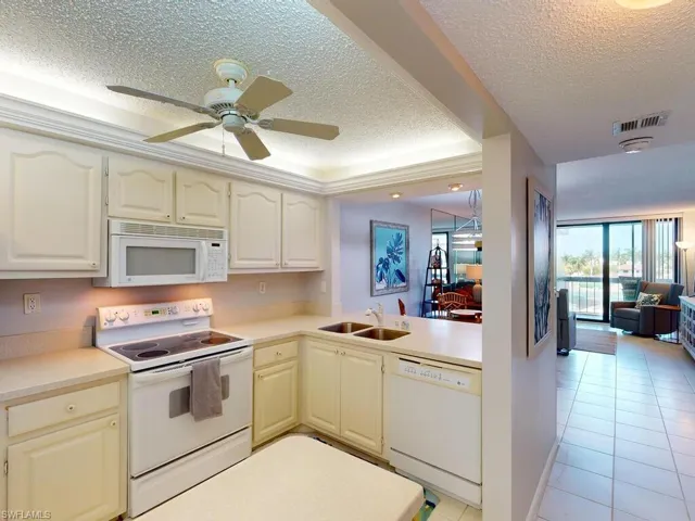 Kitchen featuring white appliances, a textured ceiling, light tile patterned floors, sink, and ceiling fan
