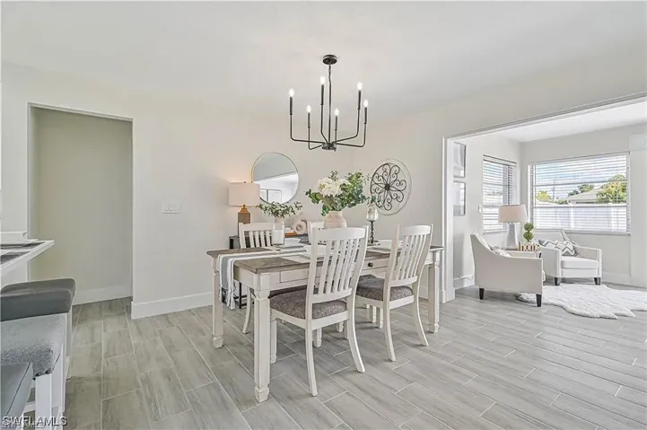 The dining area features light-toned flooring, a contemporary chandelier, and a wall mirror, creating a welcoming atmosphere