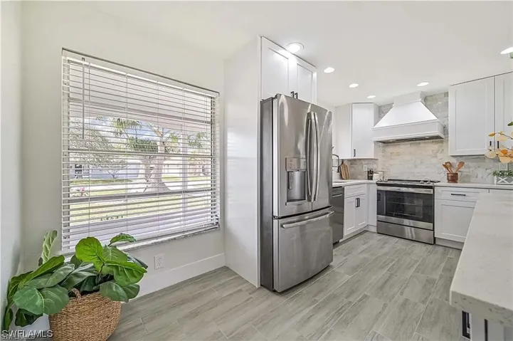 The kitchen features light-colored flooring, white cabinetry, a stainless steel refrigerator, and a stainless steel oven