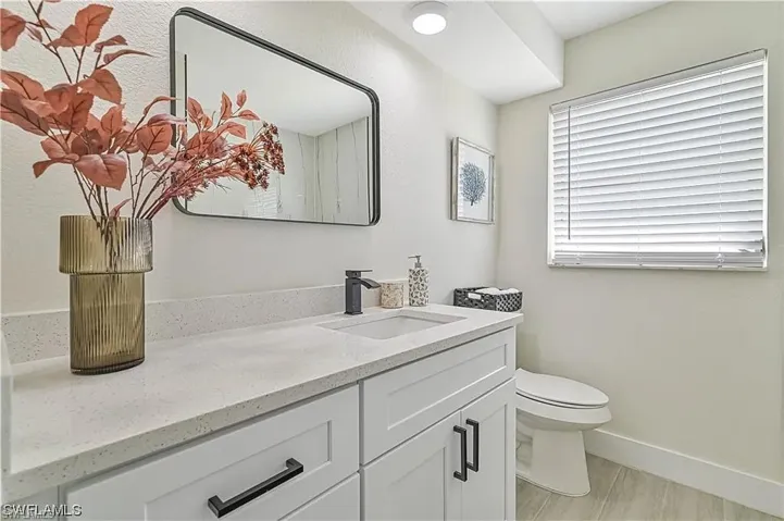 Well-appointed bathroom featuring a vanity with a white countertop, an integrated sink, and dark hardware on the cabinetry