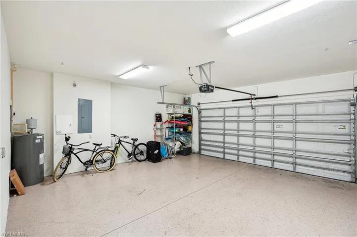Garage featuring electric water heater, electric panel, and a garage door opener