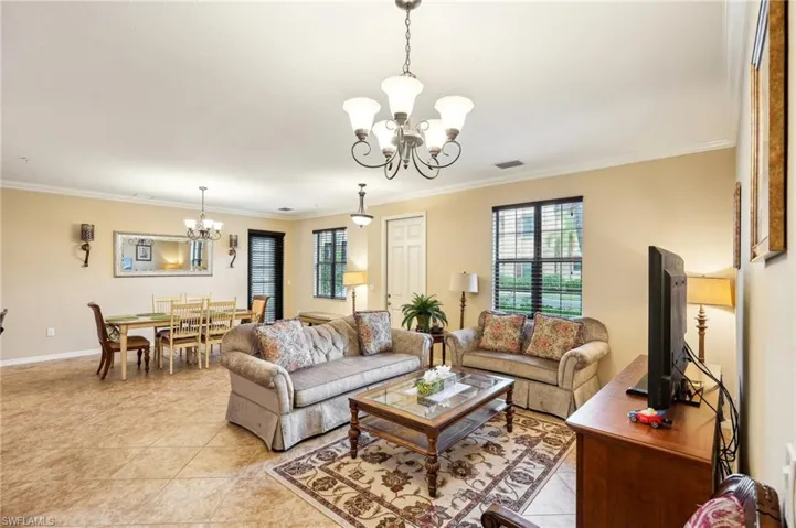 Tiled living room featuring crown molding and a notable chandelier